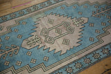 Serrated dusty mauve medallion with ram's horn plants and sky blue starburst border.