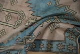 Distressed texture of the Oushak rug with sky blue starburst border and pale mauve field.