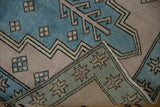 Folded corner of distressed Vintage Oushak rug runner reveals back, geometric motifs, and starburst border.