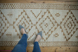 Textured pile of a distressed Kars runner with ivory and coffee geometric motifs and arrowed border.