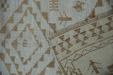 Distressed ivory and coffee brown pile texture with geometric flat-woven back of a Kars runner.