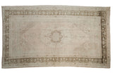 Vintage distressed Oushak carpet with a faded medallion and geometric border in pale dusty rose and ivory.