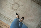 Short, even pile and faded floral pattern on a distressed vintage Oushak rug.
