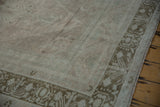Geometric floral border and distressed short pile in dusty rose and pale green tones.