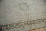 Storied wear on the short pile and faded sage green geometric border of an Oushak carpet.