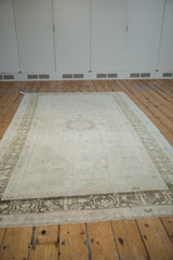 Angled perspective of a distressed Oushak rug, showing its full length and faded tones.