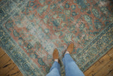 Distressed texture of a vintage Persian Lilihan carpet with dusty peach and blue floral motifs.