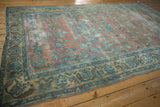 Vintage distressed Lilihan rug corner with worn pile and faded floral motifs in blue and peach.