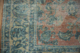 Distressed vintage Persian Lilihan carpet, dusty peach and blue floral motifs, showing foundation.
