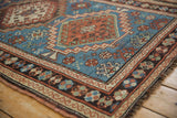 Geometric guls and hook motifs in indigo, madder red, and charcoal on this vintage Caucasian rug.