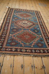 Detail of a vintage Caucasian rug showing indigo and red geometric motifs with wear.