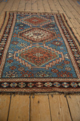 Short fringe and geometric floral border in charcoal brown on a vintage Caucasian rug.