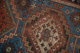Vintage Caucasian rug's stepped medallion, hook and latch motifs. Indigo, madder red, ivory, mostly even wear.