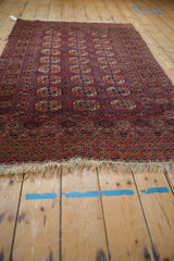 Tattered ivory fringe and intricate navy, fuchsia, brown geometric border of a vintage Turkmen rug.