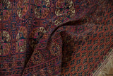 Folded vintage Turkmen rug featuring geometric guls, detailed borders in fuchsia, navy, and chestnut.