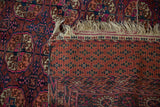 Corner detail of vintage Turkmen rug displaying geometric guls, frayed fringe, and dense back weave.