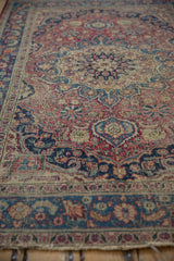 Intricate arabesque and pinwheel floral patterns in dusty red and blue, showing storied patina.