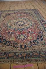 Vintage Meshed rug's worn field displaying dusty red, navy, and sky blue boteh designs.
