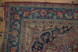 Vintage Meshed rug's worn corner, revealing tattered end and dusty red, sky blue florals.