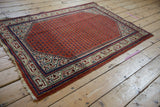Vintage Mir Sarouk rug corner detail: brick red boteh field, intricate ivory, indigo border, tattered fringe.
