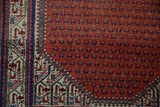 Close-up of vintage Mir Sarouk rug showing brick red boteh field and ivory Serbend border.
