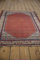 Corner of vintage Mir Sarouk rug: brick red boteh field, ivory and blue Serbend border, tattered fringe.