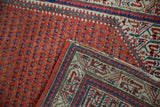 Close-up of vintage Mir Sarouk rug, revealing hand-knotted foundation and brick red boteh pattern.