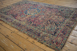 Vintage Meshed rug with dusty red and blue floral design, displaying notable wear and frayed edges.