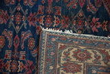 Folded corner of a vintage Lilihan rug reveals its hand-knotted foundation and tattered end.
