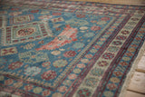 Textured pile of a distressed Caucasian rug, featuring geometric pinwheel florals and dusty reds.