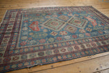 Distressed Caucasian rug border with dusty blue, brick red geometric and floral motifs.