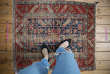 Antique Heriz rug's wide cherry red border with indigo floral patterns, showing wear.