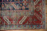 Antique Heriz rug corner detail, with worn cherry red field and blue borders, tattered edge.