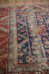 Significant pile wear and exposed foundation on an antique Heriz rug, with indigo and red vinery.