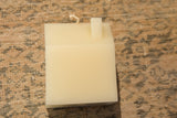 Cream house-shaped beeswax candle with exposed wick.