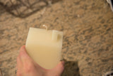 Cream beeswax house candle, held by hand, showing the top and wick.