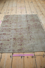 Antique Kerman rug fragment with distressed pile, visible foundation, and faded blush boteh motifs.