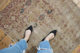 Antique Kerman rug detail: worn pile, visible foundation, faded ivory, red millefleur pattern.