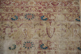 Distressed texture of an antique Kerman rug, with exposed foundation and faded blossomed florals.