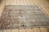 Distressed Kerman rug's worn pile, highlighting cochineal red floral designs and navy blooms.