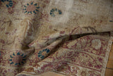 Distressed texture of an antique Kerman rug, showing faded cochineal red florals.