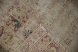Folded corner of antique Kerman fragment, revealing distressed pile, exposed foundation, and faded floral patterns.