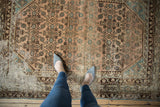 Close-up of distressed vintage Hamadan rug, showing worn dusty rose Herati pattern and foundation.