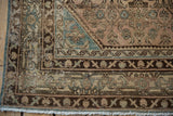 Distressed Hamadan rug corner, showing chocolate brown Samovar turtle border, muted field patterns and fringe.