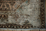 Distressed Hamadan rug corner, showing exposed foundation, dusty rose field, and dark border.