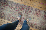 Antique Kerman runner's distressed curvilinear floral patterns in cochineal red and ivory.