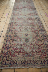 Close-up of antique Kerman runner's distressed cochineal red palmettes and sea foam green field.
