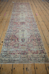 Antique Persian Kerman runner rug with distressed cochineal red and blue floral motifs on ivory.