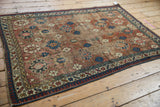 Intricate indigo starburst border and red geometric palmettes with visible wear on a vintage Caucasian rug.