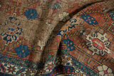 Geometric palmettes, madder red field, and an indigo pawn border with storied wear.